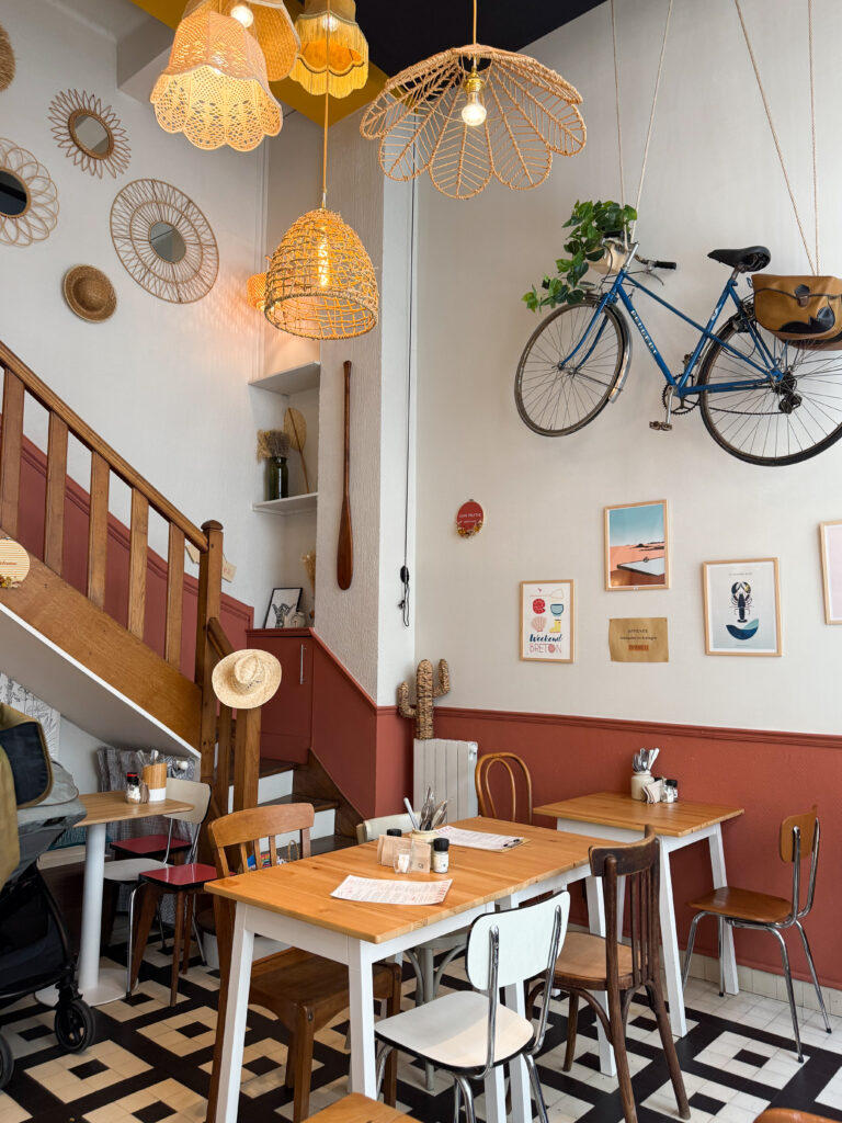 une salle de restaurant avec un escalier, deux tables, un vélo, des lampes et des tableaux sur le mur