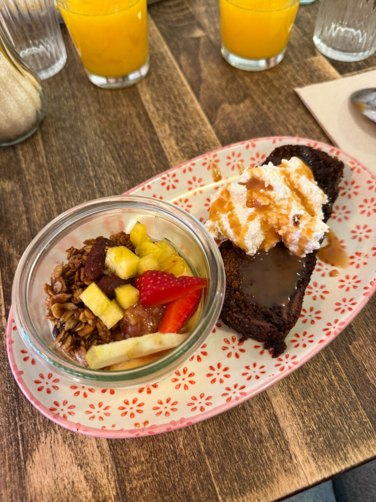 une table avec une assiette de granolat maison et un gateau au chocolat et 2 jus d'orange
